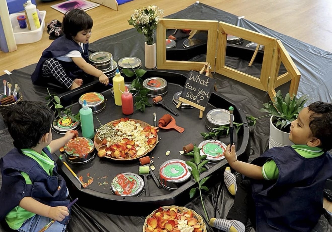An atelier invitation with paint, petals and mirrors, and room for children's ideas