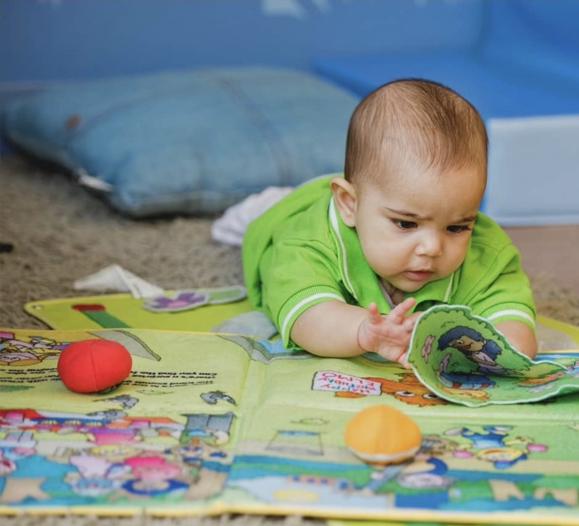 A baby exploring picture books in a calm nursery setting
