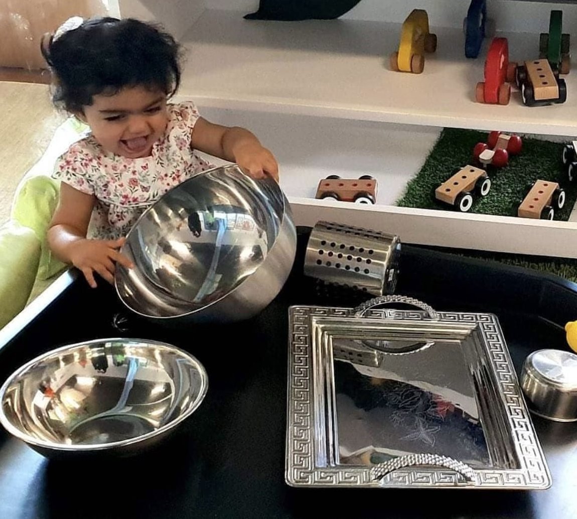 A baby exploring everyday metal bowls, trays and kitchen objects